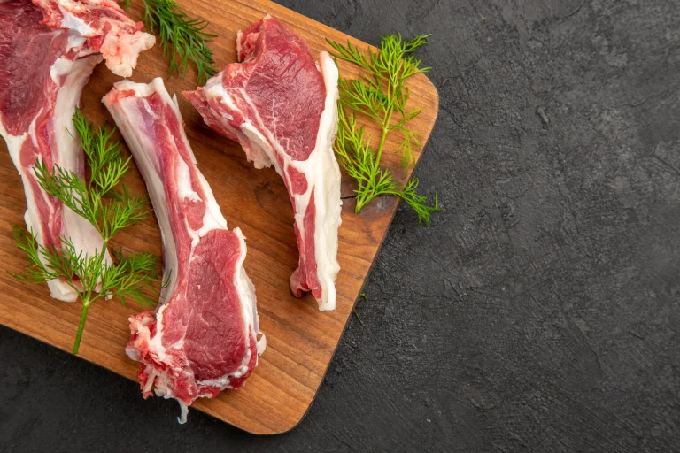 top-view-raw-meat-slices-with-greens-dark-background-cow-color-meat-photo-animal-pepper-chicken-raw-free-space